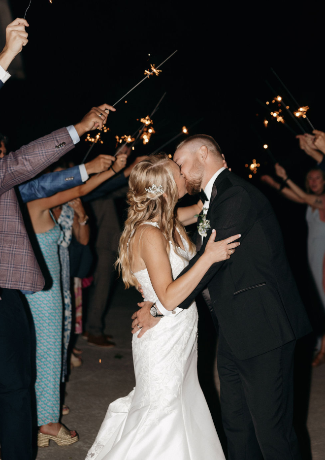 Bride and groom kissing at sparkler exit